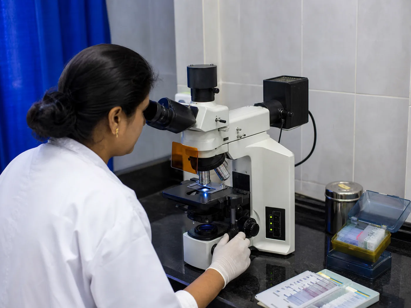 Laboratory technologist using a fluorescence microscope at Mangala Hospital